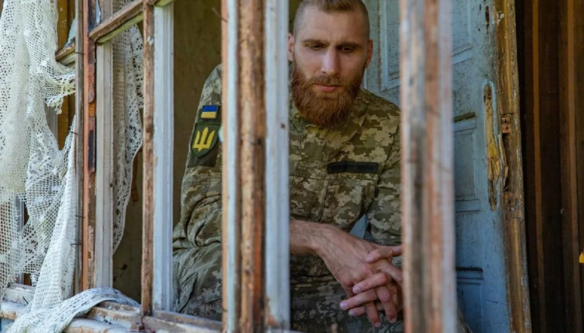 Павло Вишебаба у військовій формі на тлі зруйнованого будинку