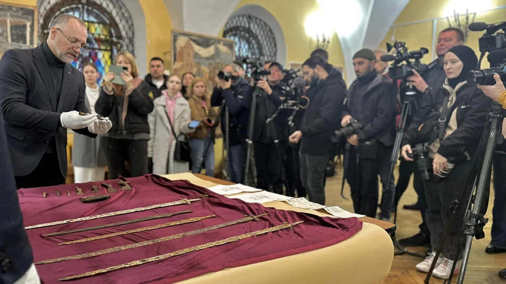 Чоловік у рукавичках демонструє викрадені артефакти журналістам у Брістолі
