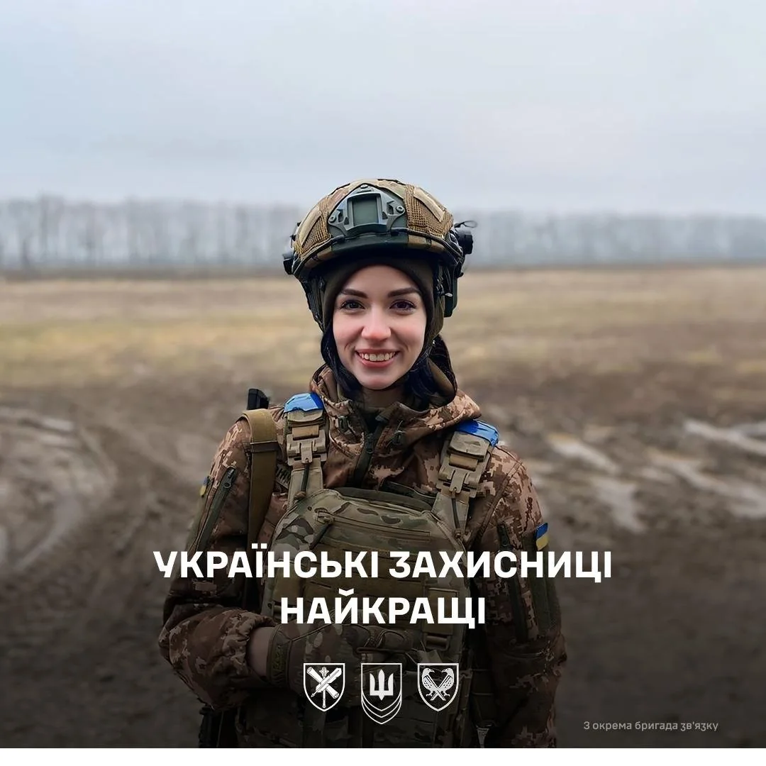 Усміхнена українська захисниця в камуфляжі шоломі та бронежилеті на полі